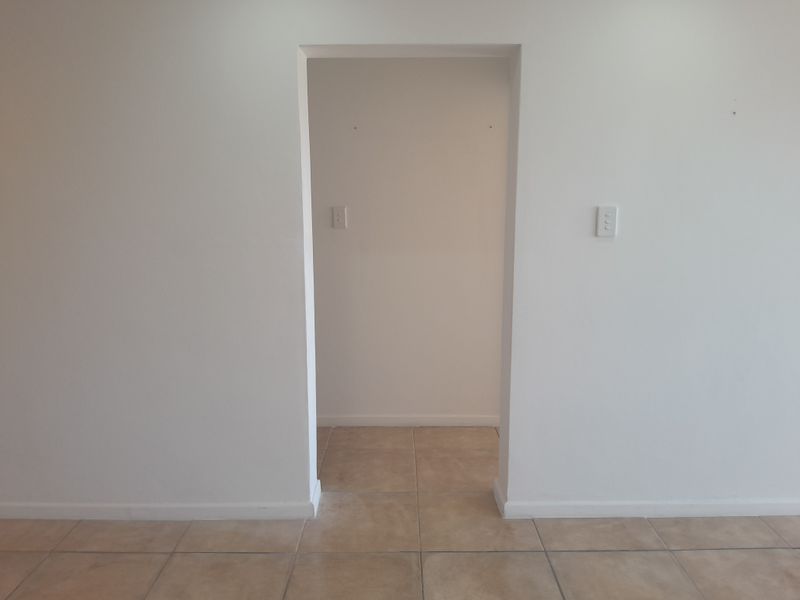 A simple, empty transition space featuring neutral tiled flooring and white walls, providing a clean canvas for interior design.