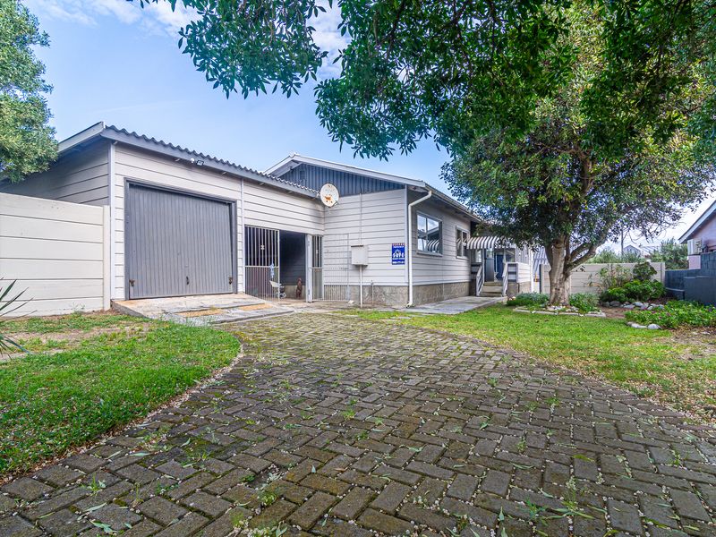 Front exterior view of the property featuring a paved driveway, single garage, and established garden area.