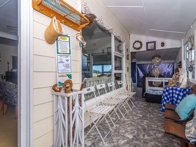 Enclosed patio area featuring weatherboard wall cladding, tiled flooring, and large windows, offering a functional transition space between the interior and exterior.