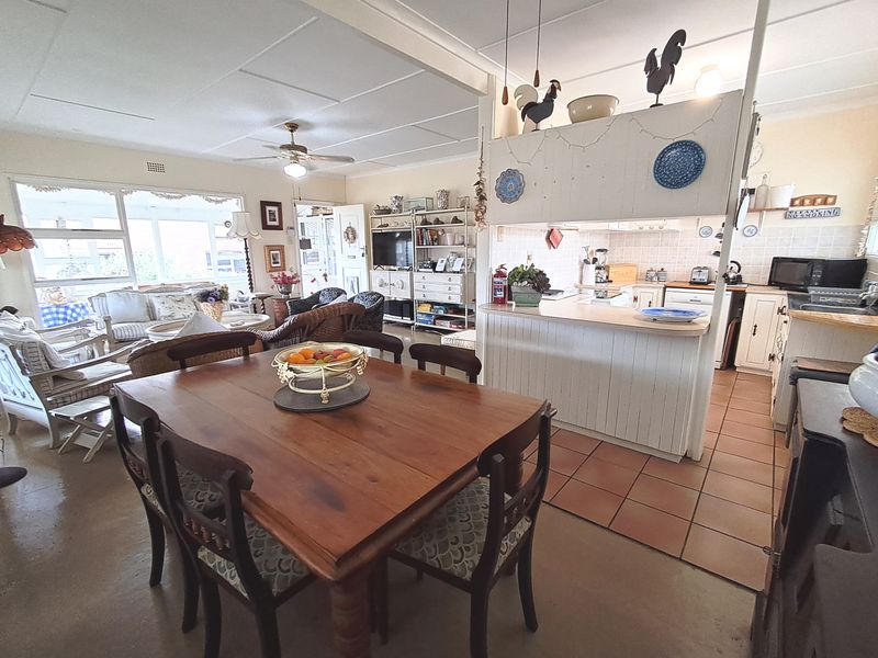 Open-plan living, dining, and kitchen area featuring a breakfast bar, tiled kitchen flooring, and ample natural light from large windows.