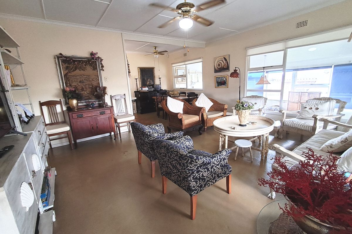 Spacious living area featuring large windows, ceiling fans, and neutral tiled flooring, offering a bright and comfortable space for relaxation.