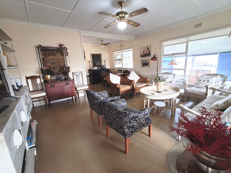 Spacious living area featuring large windows, ceiling fans, and neutral tiled flooring, offering a bright and comfortable space for relaxation.