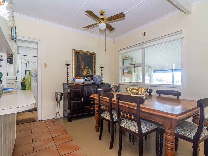 A functional dining area featuring tiled flooring, a ceiling fan, and a large sliding window providing natural light.