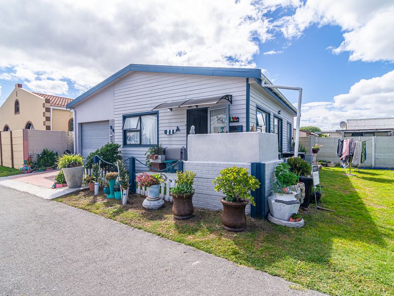 Front exterior view of a single-story house featuring weatherboard cladding, a garage, and a small front garden area.