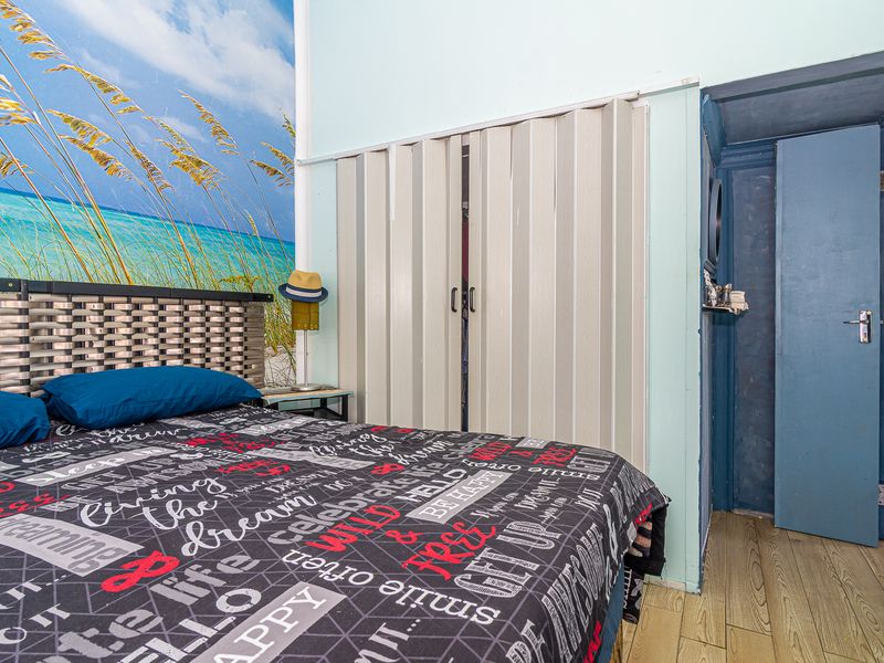 A bedroom featuring laminate flooring and built-in folding closet doors, providing functional storage space within the room.