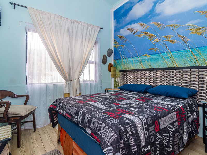 A bedroom featuring laminate flooring and a large wall mural. The room requires cosmetic updates to the wall finishes.