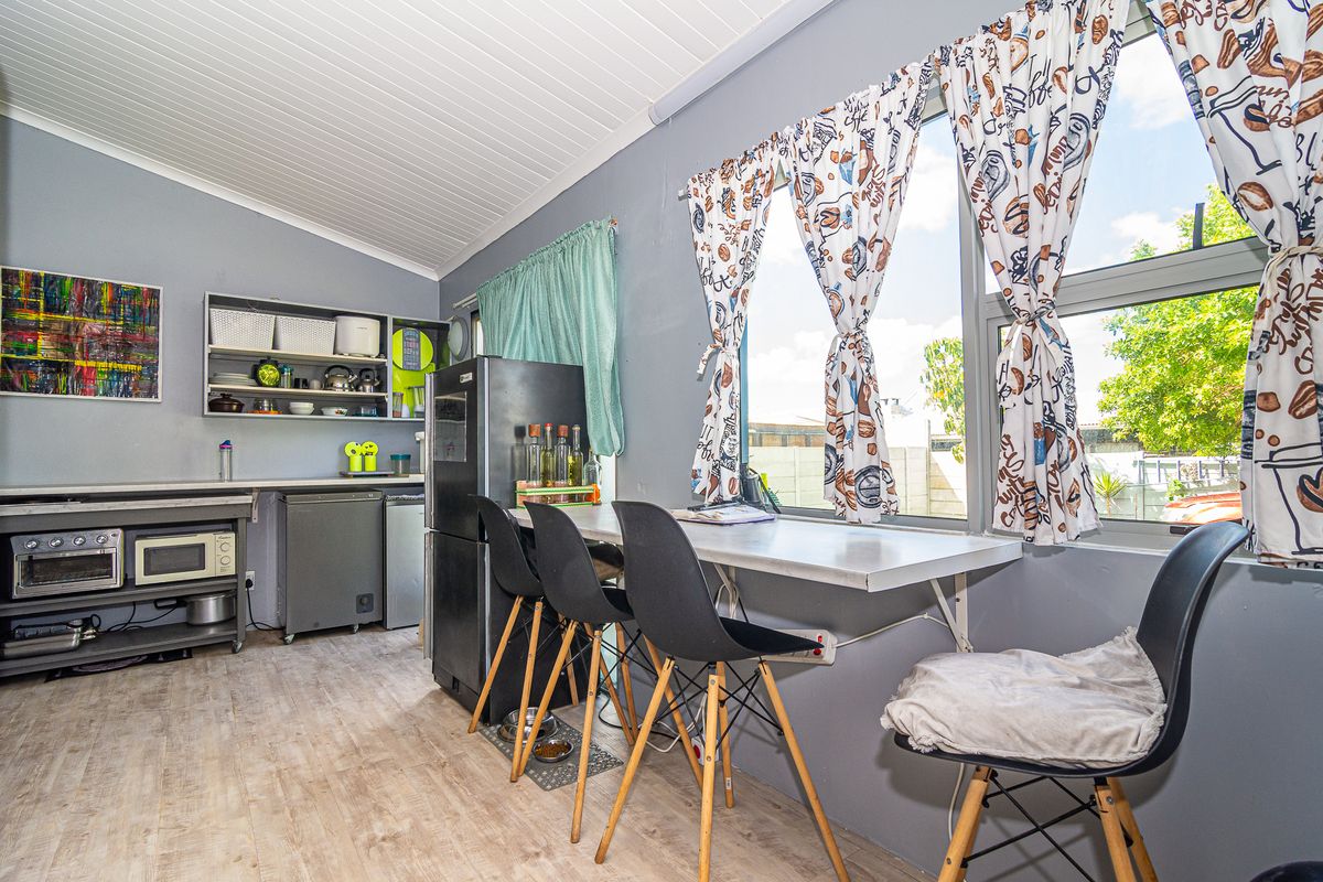 A compact kitchen area featuring a built-in breakfast bar, laminate flooring, and tongue and groove ceiling with ample natural light.
