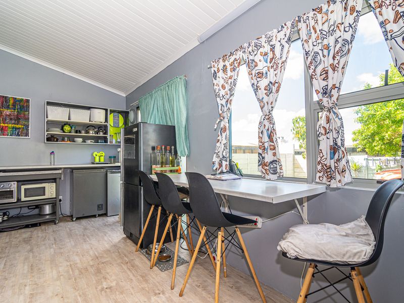 A compact kitchen area featuring a built-in breakfast bar, laminate flooring, and tongue and groove ceiling with ample natural light.