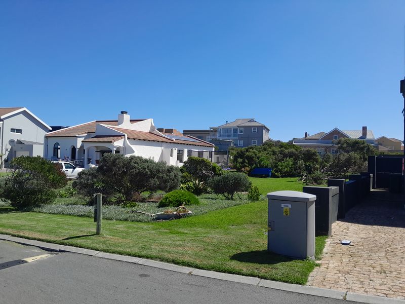 A view of the front garden and landscaped area of the residential property, featuring a paved driveway and established greenery.