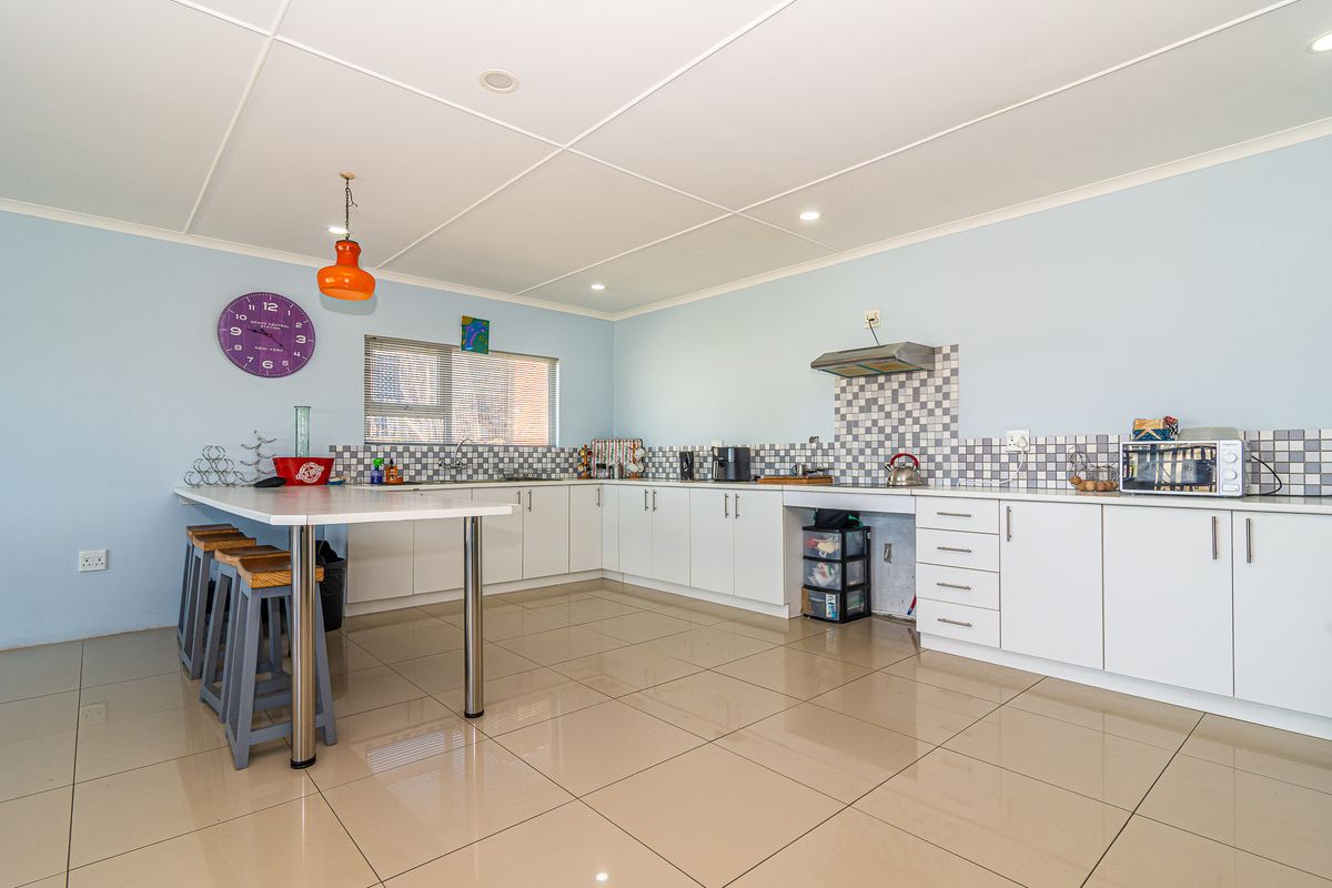 A functional kitchen featuring white cabinetry, tiled backsplash, a breakfast bar, and tiled flooring, offering a clean and practical workspace.