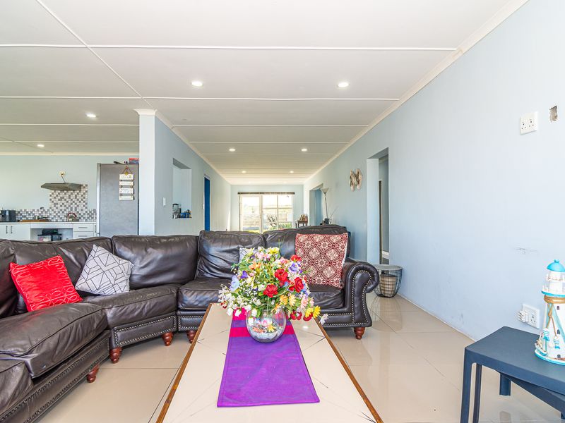 Spacious open-plan living area featuring tiled flooring, recessed lighting, and a connected kitchen space with built-in cabinetry and a tiled backsplash.