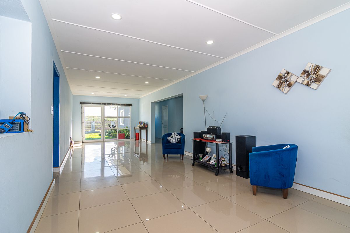 Spacious living area featuring polished tiled flooring, recessed downlighting, and a sliding glass door providing natural light and access to the exterior.