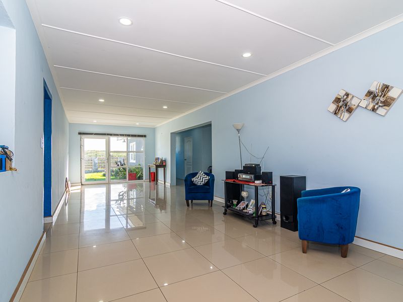 Spacious living area featuring polished tiled flooring, recessed downlighting, and a sliding glass door providing natural light and access to the exterior.