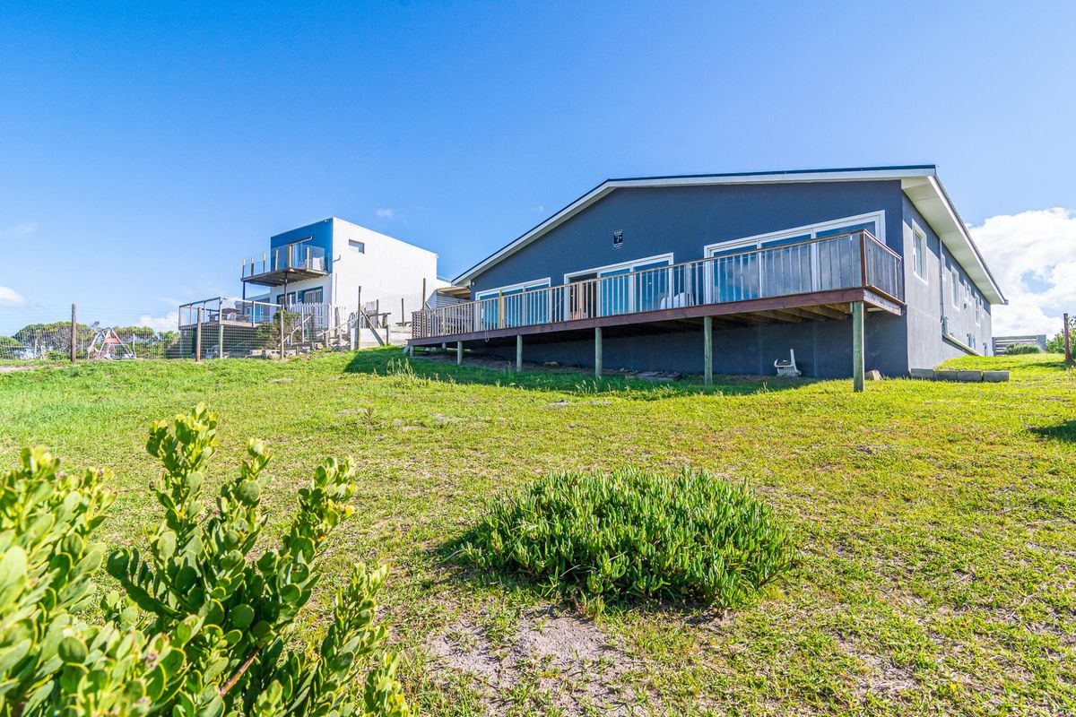 Rear view of the property featuring a raised timber deck with metal balustrades and large sliding glass doors leading into the home.