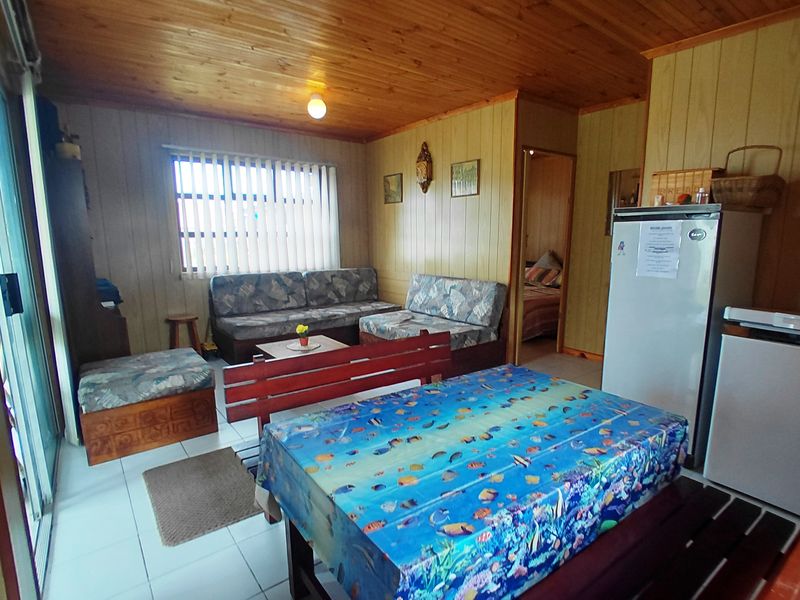 Open plan living and dining area featuring timber wall paneling, tongue and groove ceiling, tiled flooring, and access to an outdoor area via sliding doors.