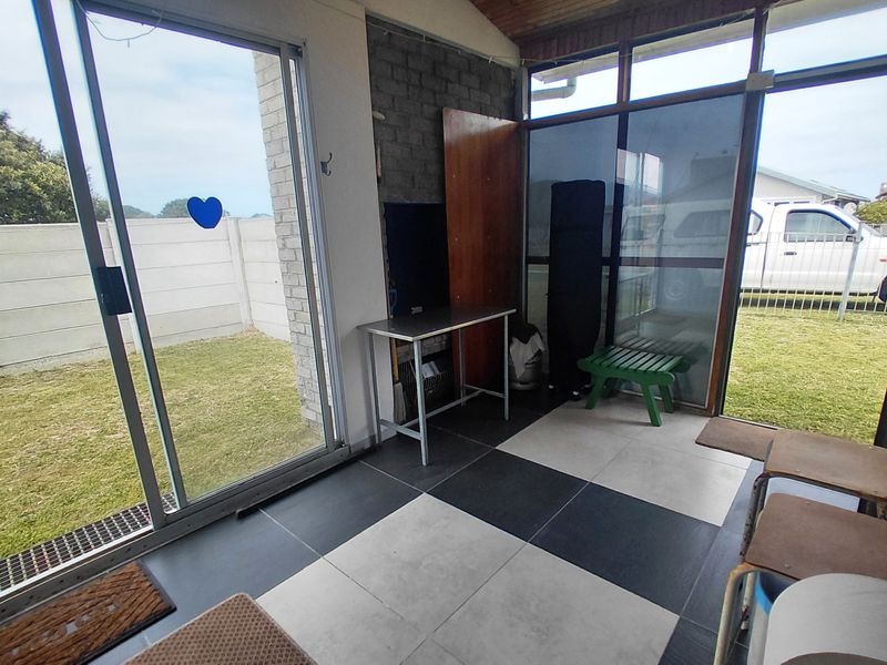Enclosed patio area featuring large sliding glass doors, tiled flooring, and exposed brickwork, offering direct access to the rear garden.