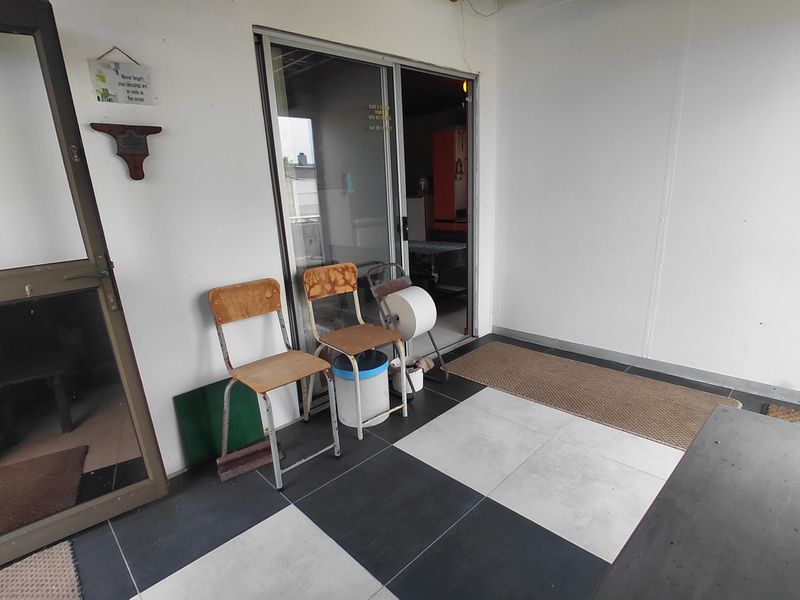 A covered patio area featuring a sliding glass door entrance and a checkered tiled floor.