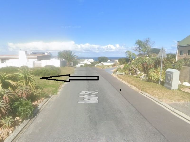 A street view of Mark Street showing the residential approach, paved road, and surrounding landscaped verges in a coastal neighborhood.