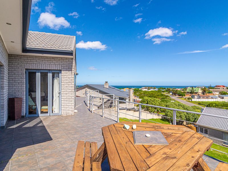 Spacious elevated balcony featuring tiled flooring, metal railings, and expansive coastal views, providing an ideal outdoor entertainment area.