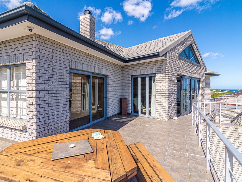 Spacious elevated balcony featuring tiled flooring, brick exterior walls, and large sliding glass doors, offering a seamless transition between indoor and outdoor living spaces.