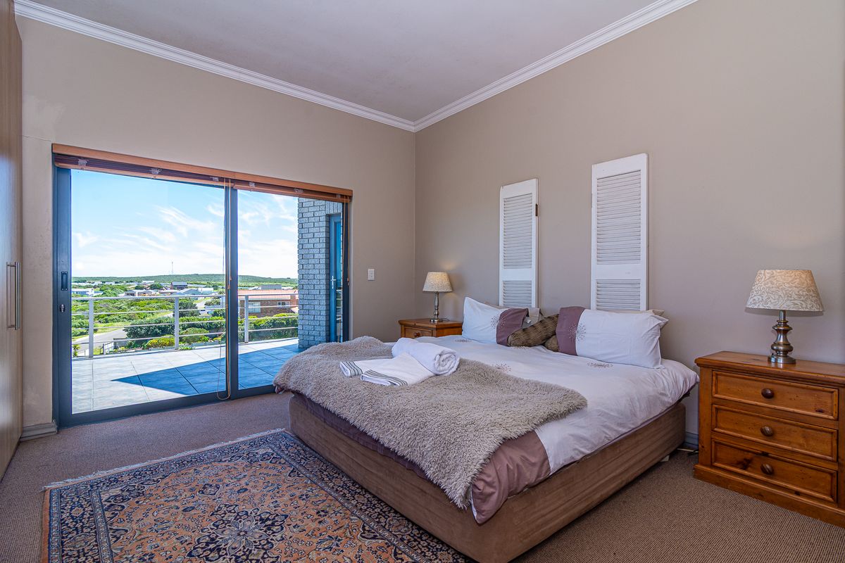 Spacious bedroom featuring neutral walls, crown molding, carpet flooring, and a large sliding glass door providing access to a private balcony with scenic views.
