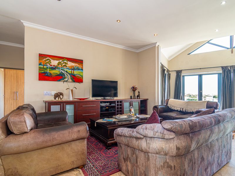 Spacious living room featuring vaulted ceilings, recessed lighting, tiled floors, and large sliding glass doors that provide natural light and access to the outdoors.