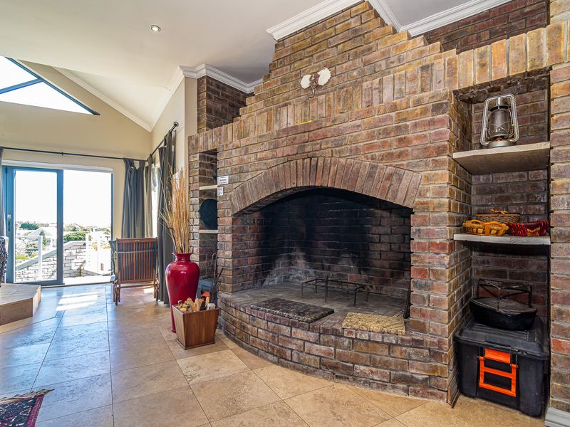Spacious living area featuring a prominent brick fireplace, vaulted ceilings, and large sliding doors that provide natural light and access to the outdoors.