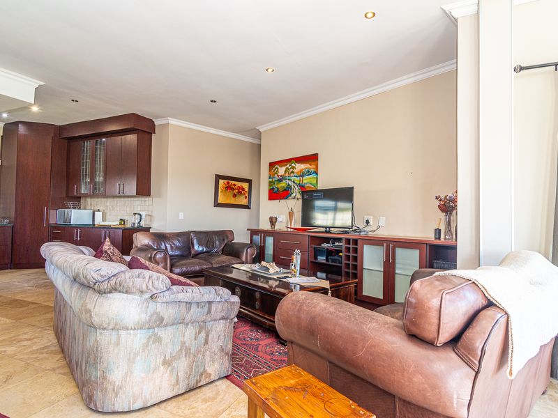 Open-plan living area featuring tiled floors, recessed lighting, and a connected kitchen with dark wood cabinetry.