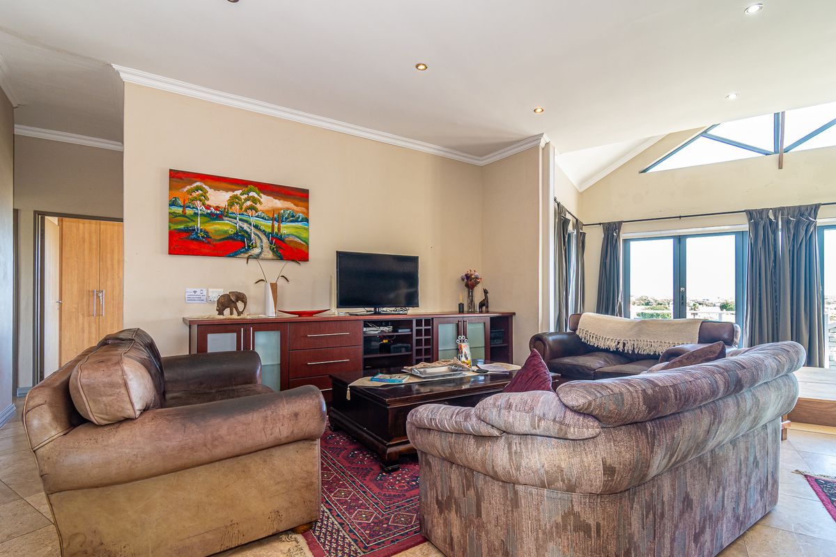 Spacious living room featuring vaulted ceilings, recessed lighting, tiled flooring, and large sliding doors providing natural light and access to the exterior.