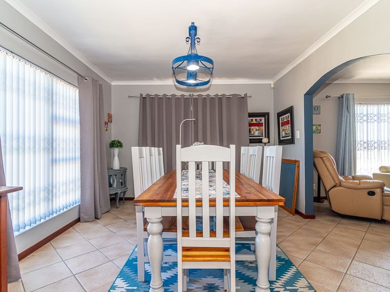 A dining room featuring ceramic tile flooring, a coved ceiling, and an arched entryway leading to an adjacent living space.