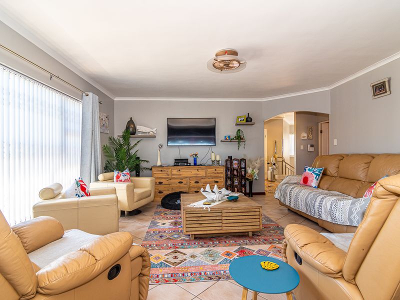 A comfortable living room featuring tiled flooring, a ceiling fan, and an arched entryway leading to the rest of the home.