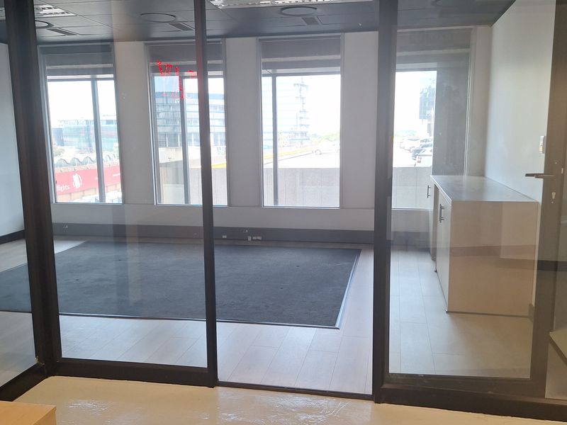 Modern office space featuring glass partitions, recessed lighting, and built-in cabinetry, offering a clean and professional environment with ample natural light.