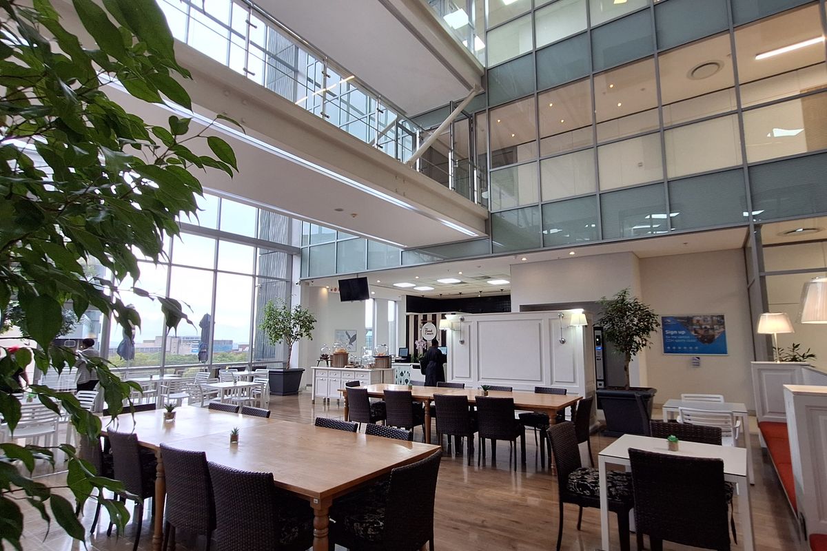 Spacious open-plan office atrium featuring high ceilings, extensive glass curtain walls, and modern hardwood flooring in a bright, multi-level commercial environment.