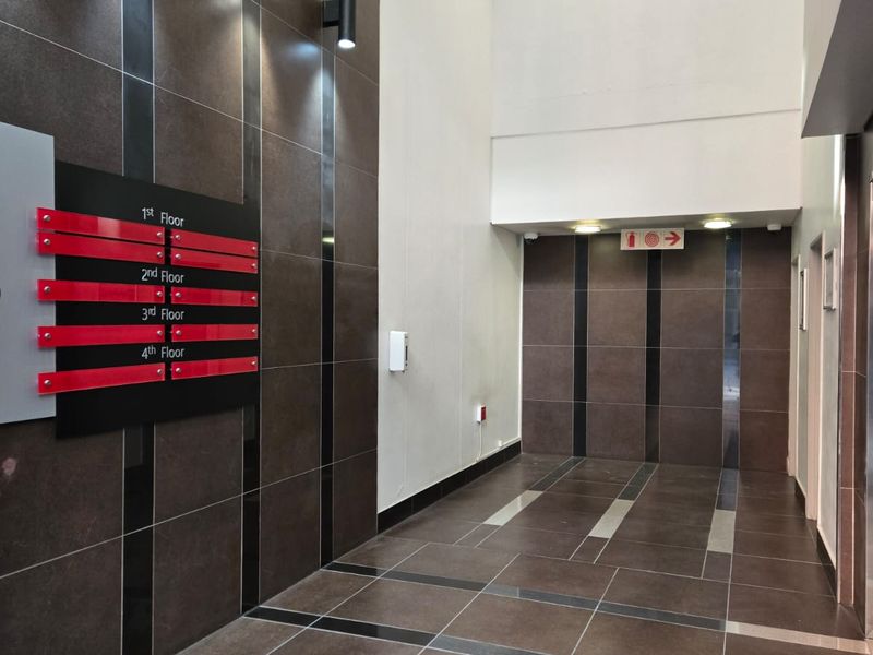 Modern office building entrance lobby featuring dark tiled walls, polished floor tiles, and clear floor directory signage.