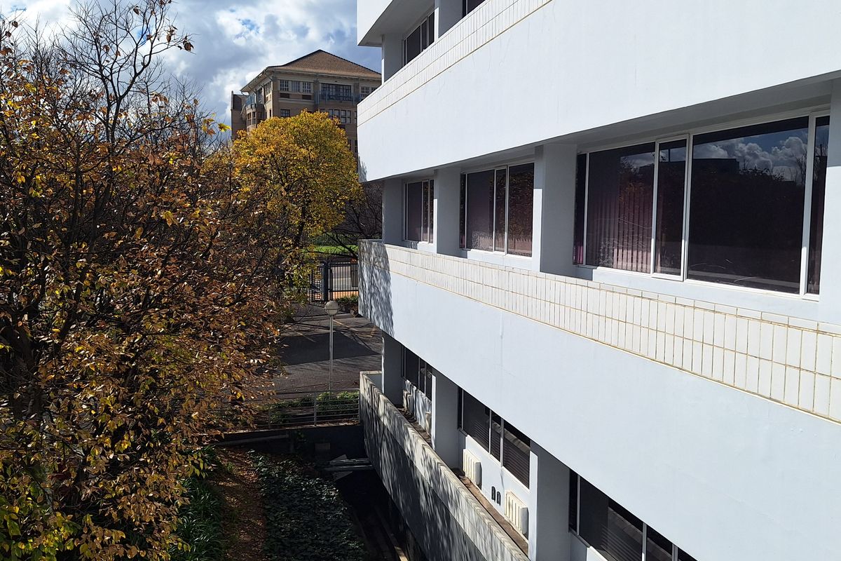 A view of the multi-story office building exterior, featuring a clean facade with aluminum-framed windows and integrated air conditioning units.