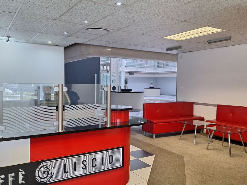 A professional office reception area featuring a built-in service desk, suspended ceiling with recessed lighting, and a combination of tiled and carpeted flooring.