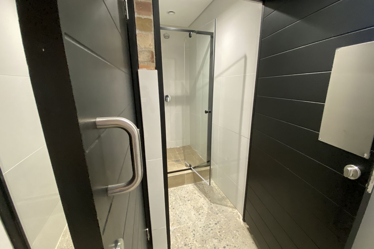 Modern industrial-style bathroom featuring a glass-enclosed shower, terrazzo flooring, and exposed brick accents.