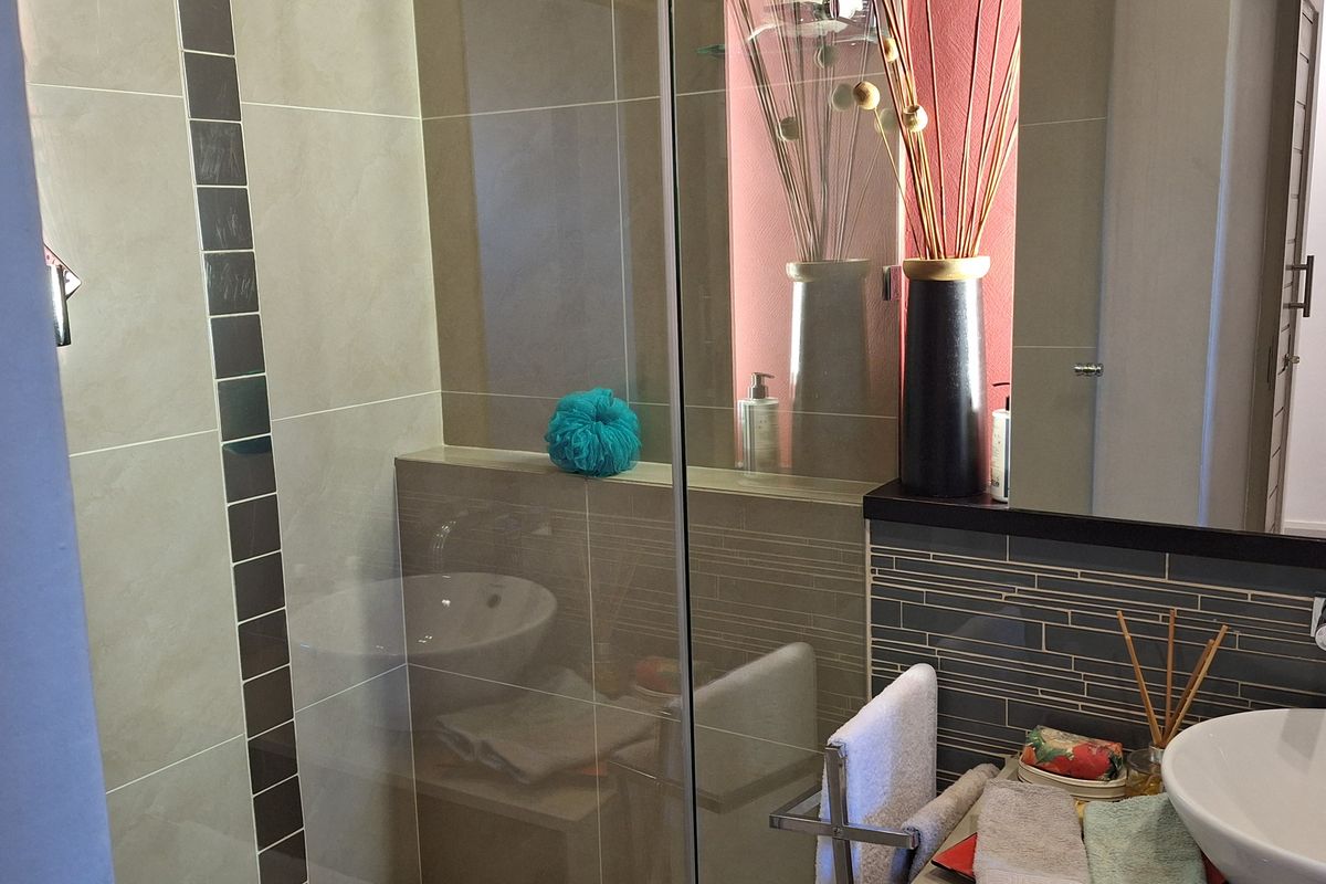 Modern bathroom featuring a glass-enclosed shower, vessel sink vanity, and contemporary tiled finishes.