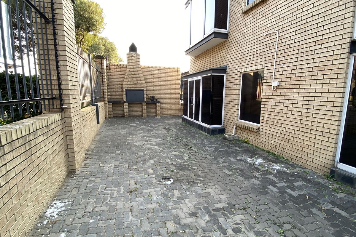 A paved rear courtyard area featuring a built-in brick braai and perimeter brick walling, providing a functional outdoor space.