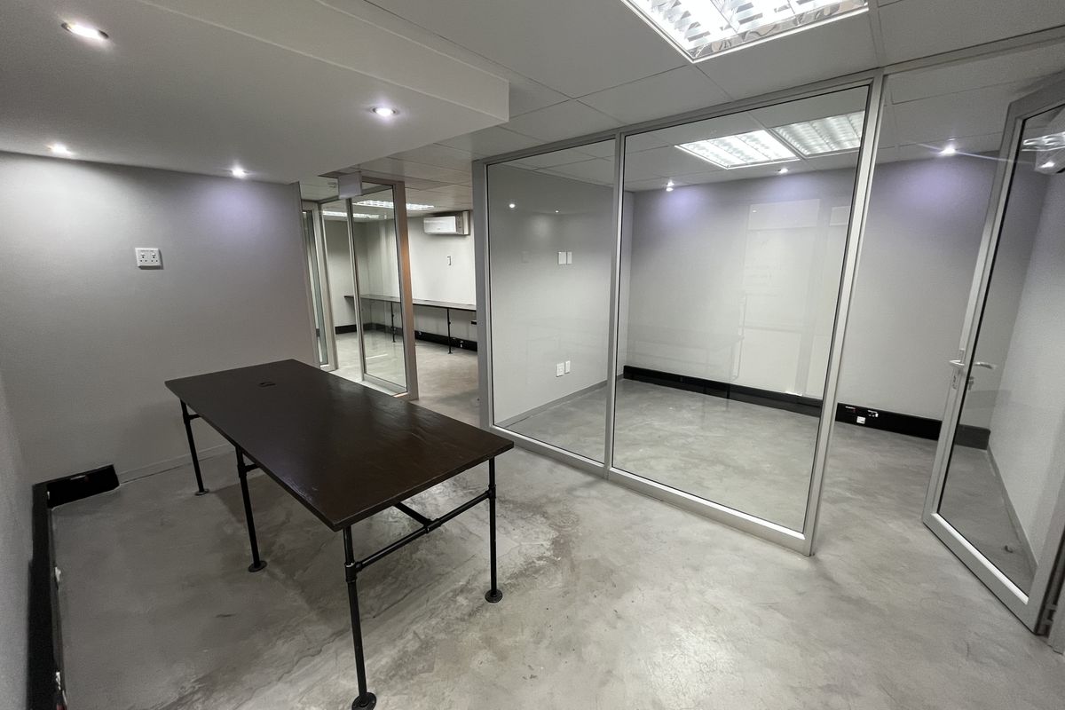 Modern office space featuring polished concrete floors, glass partitioning, and recessed lighting, offering a clean and professional environment for business operations.