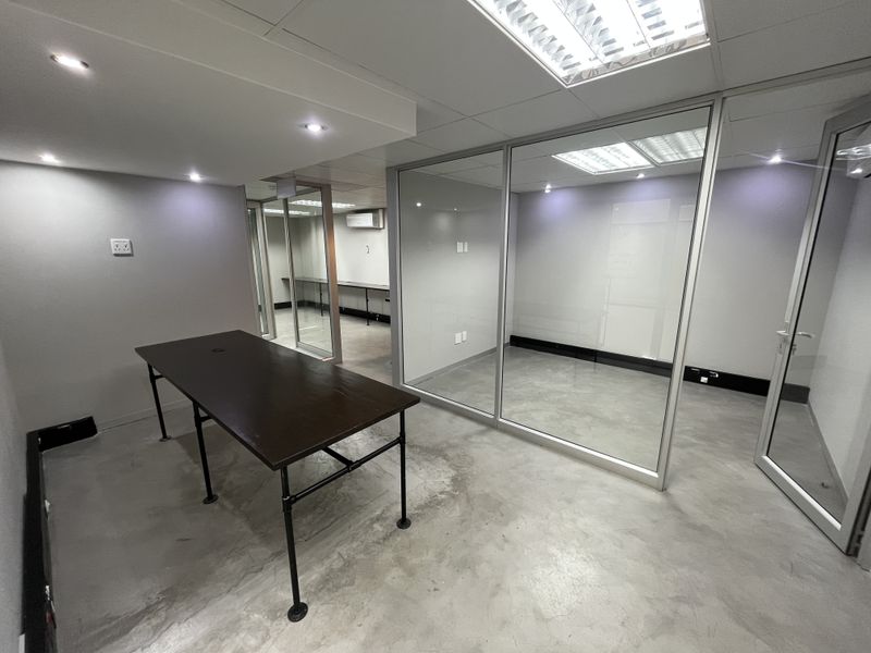 Modern office space featuring polished concrete floors, glass partitioning, and recessed lighting, offering a clean and professional environment for business operations.