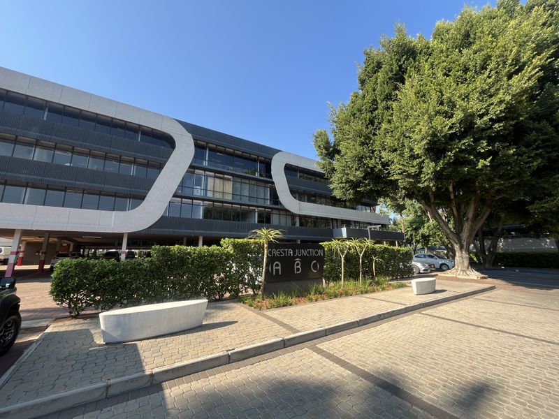 Front exterior view of the Cresta Junction office complex featuring modern architectural facade, paved driveway, and landscaped garden area.