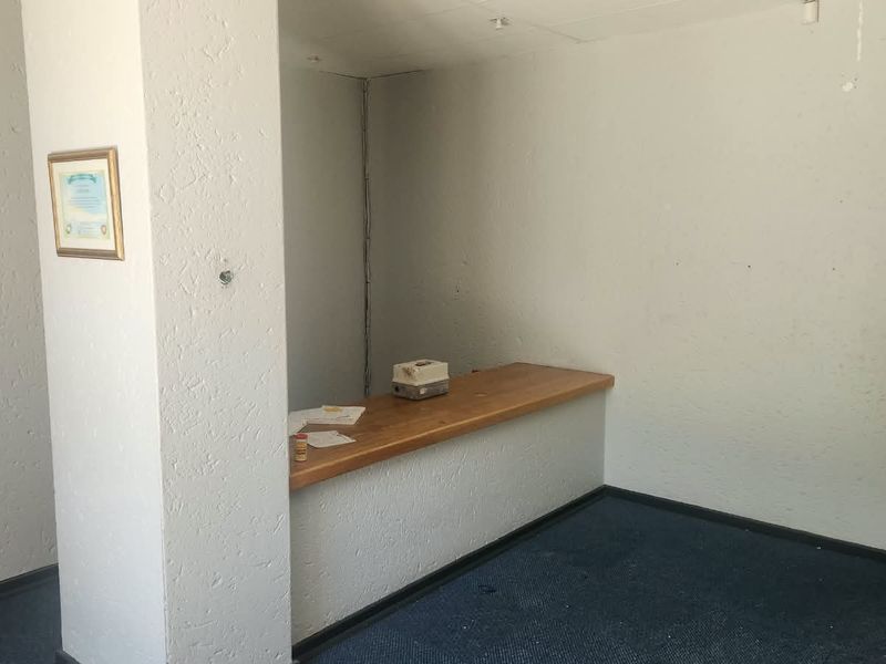 An empty utility or reception area featuring a built-in service counter, textured walls, and carpeted flooring, suitable for office or commercial use.