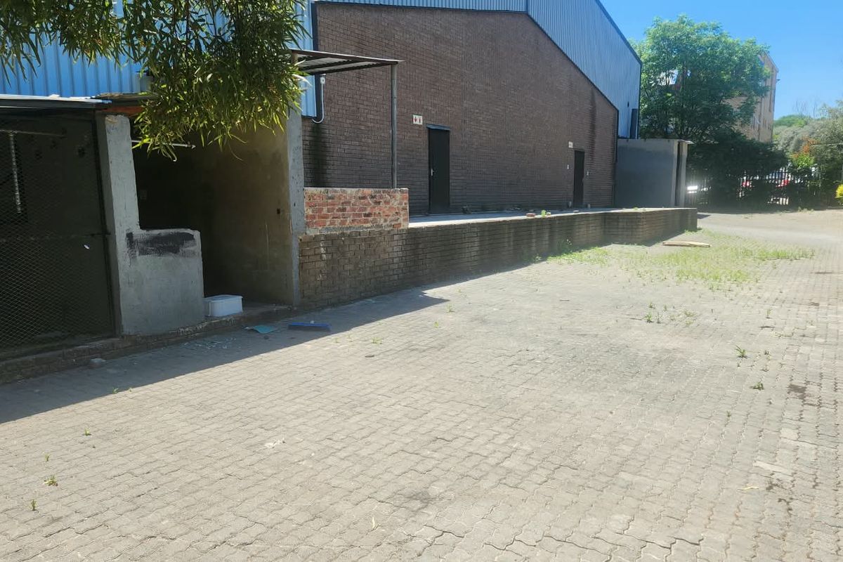 Rear industrial yard featuring a brick loading dock, paved surface, and metal-clad warehouse exterior.