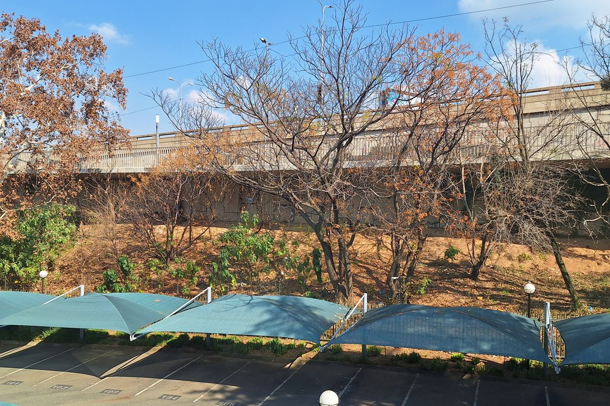 Exterior view of a paved parking area featuring multiple shade cloth carports and a retaining wall structure.