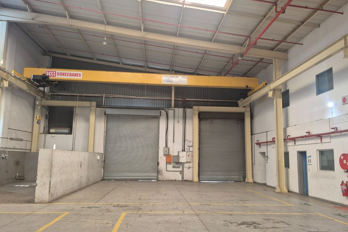 Spacious industrial warehouse featuring high ceilings, overhead crane, dual roller shutter doors, and integrated fire safety systems.