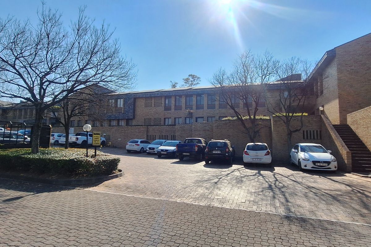 Front exterior view of the office building featuring a brick facade, paved parking area, and an external staircase leading to the upper level.