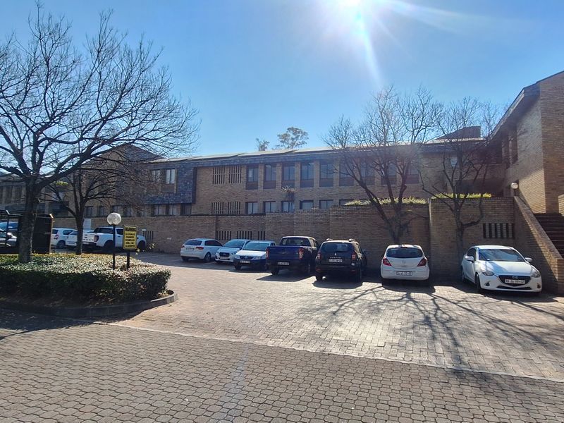 Front exterior view of the office building featuring a brick facade, paved parking area, and an external staircase leading to the upper level.