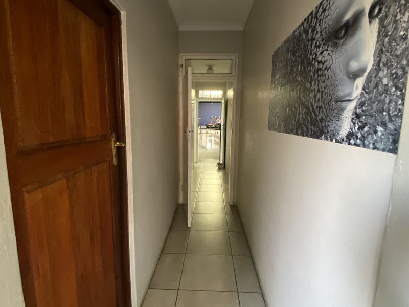 A functional hallway featuring tiled flooring and a solid timber door, providing access to adjacent rooms within the industrial property.