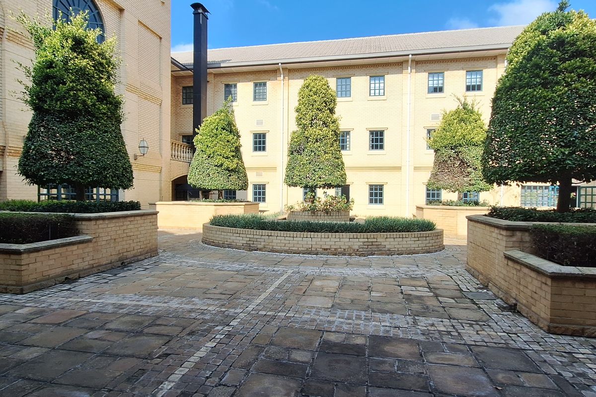 A well-maintained paved courtyard area featuring raised brick planters and a multi-story brick office building facade.